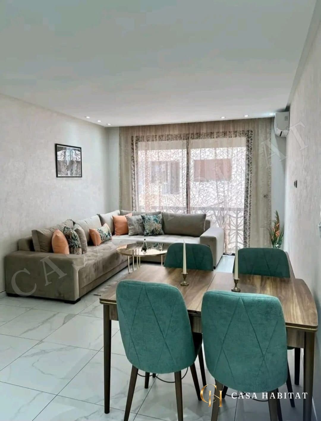 Salon avec canapé gris et chaises vertes autour d'une table