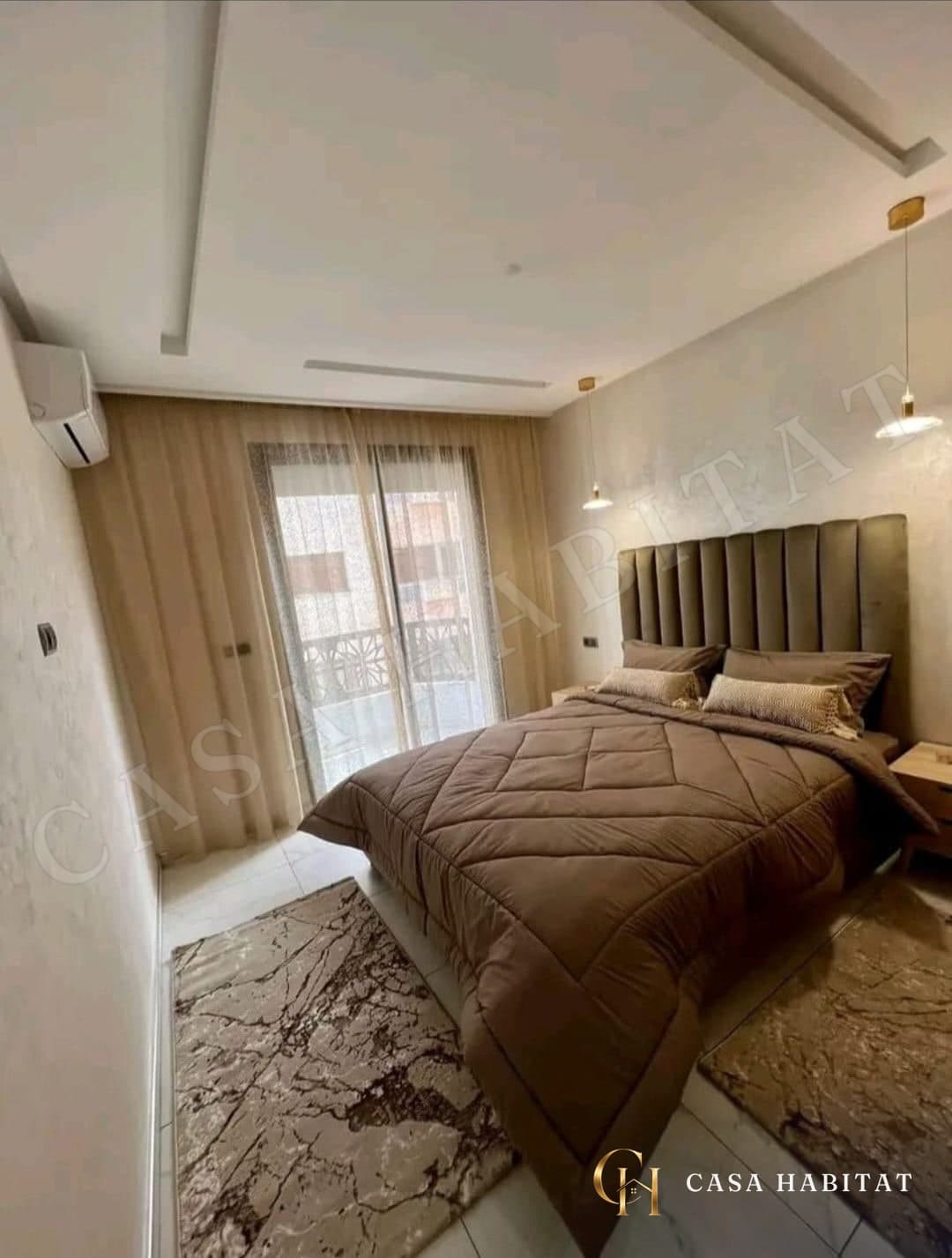 Chambre avec lit marron, porte-fenêtre et climatiseur mural
