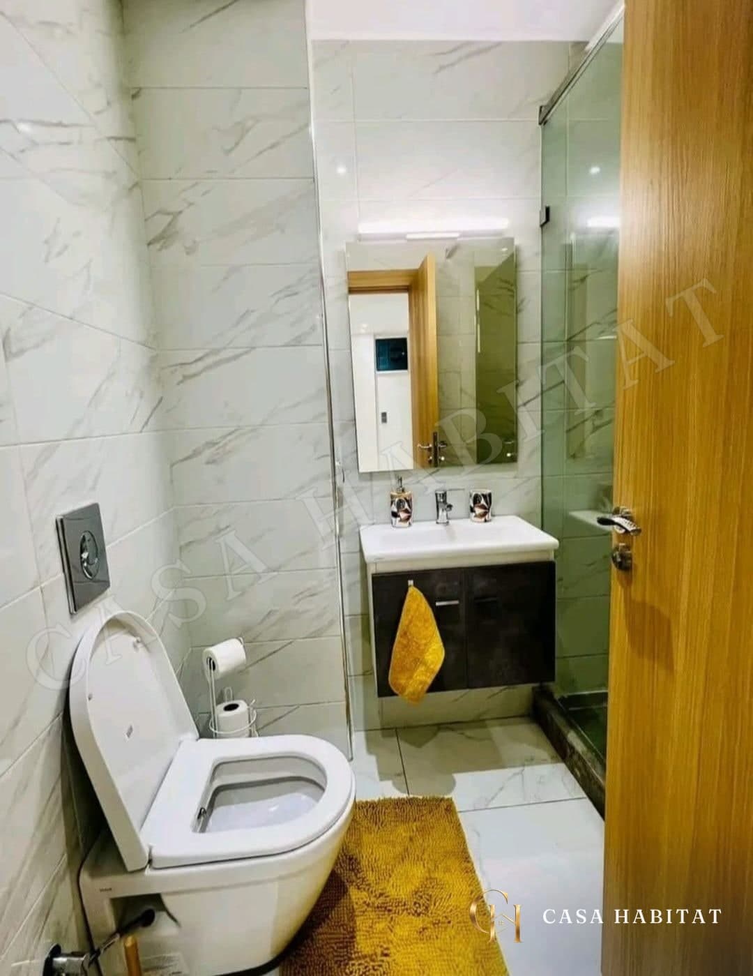 Salle de bain avec WC, vasque sous miroir et douche en verre