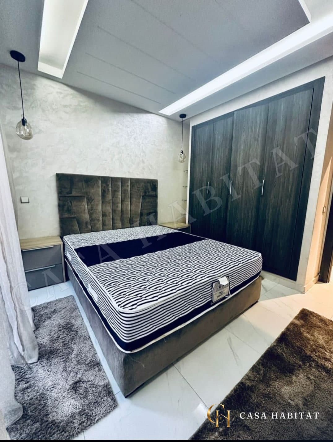 Chambre avec lit double, tête de lit capitonnée et placard en bois sombre