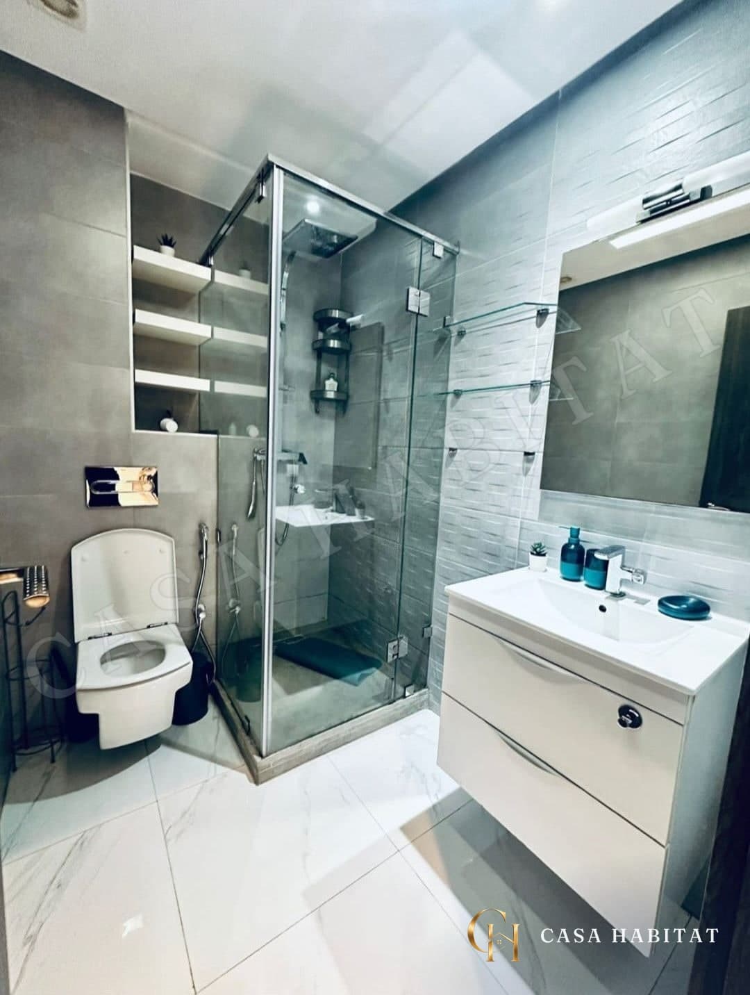Salle de bain avec douche en verre et étagères murales blanches