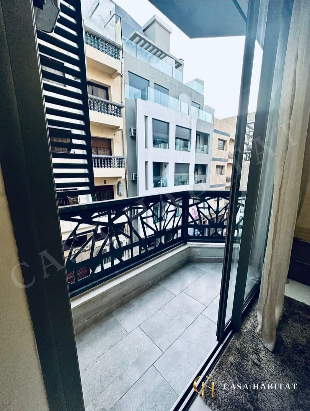 Balcon avec garde-corps en métal ajouré donnant sur des immeubles