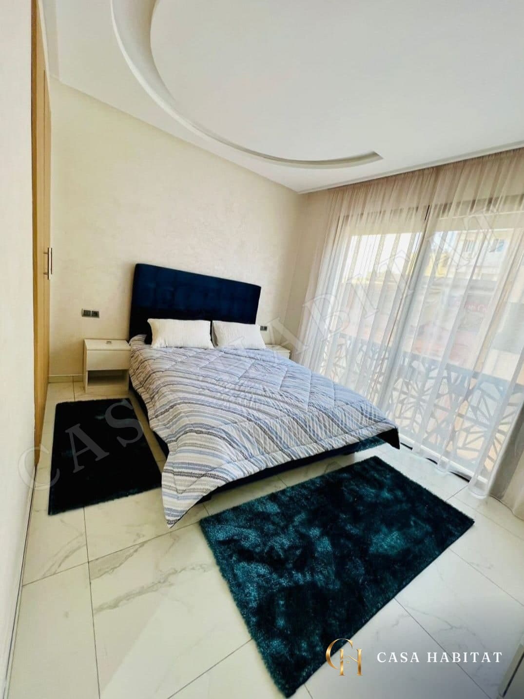 Chambre avec lit bleu, tapis bleus et rideaux translucides