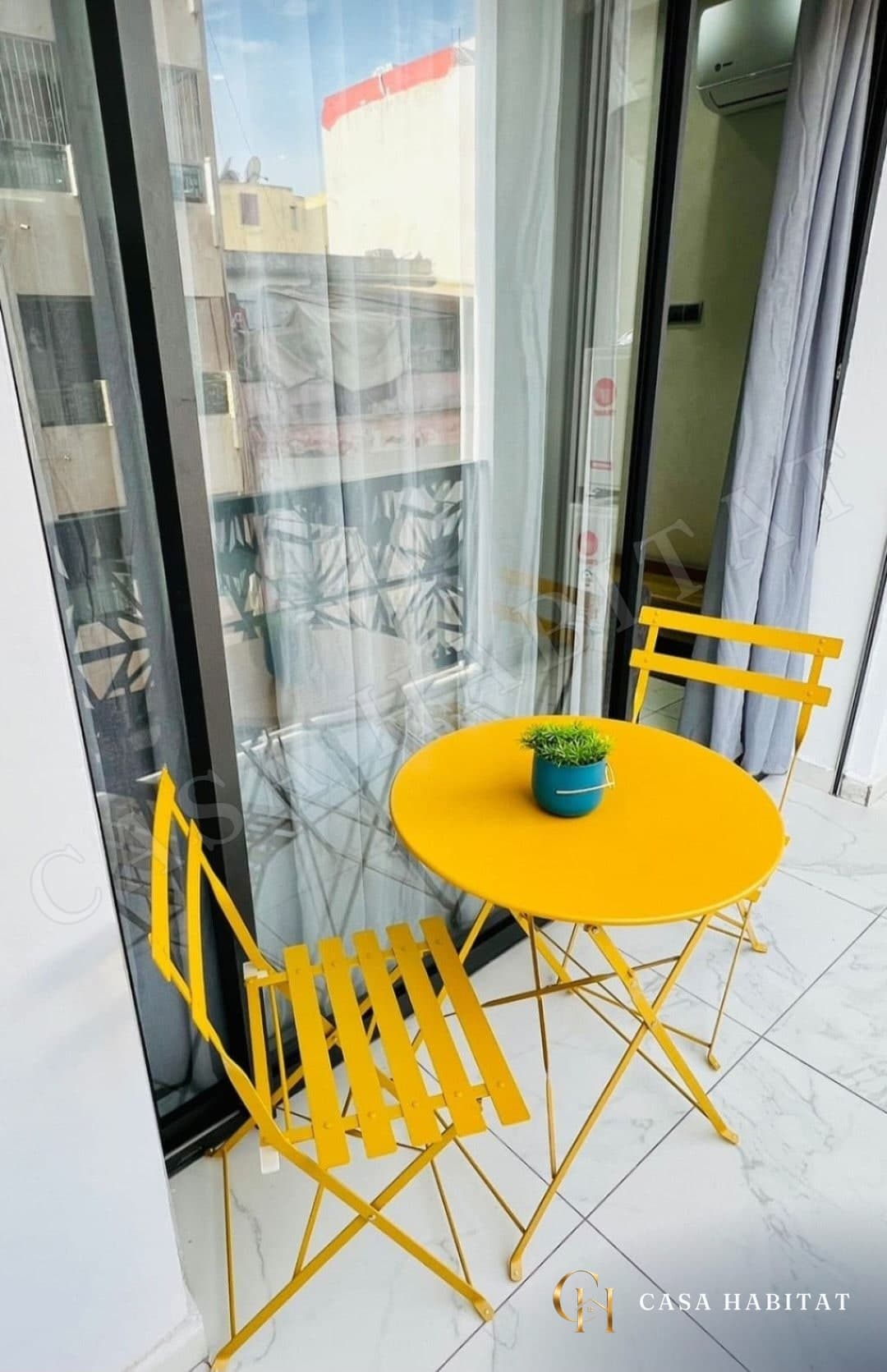 Balcon avec table et chaises jaunes, plante verte