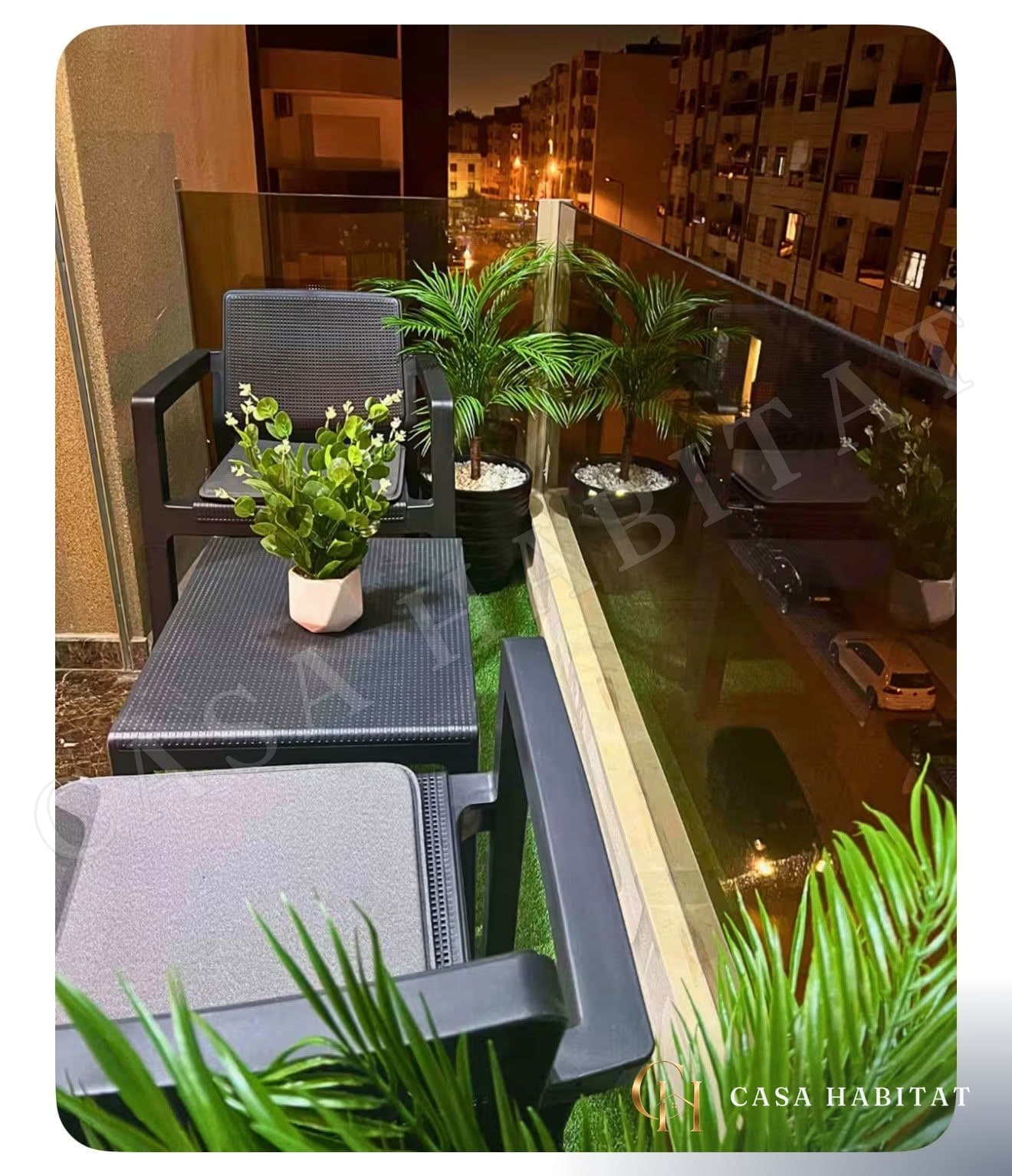 Balcon avec deux fauteuils noirs, table basse et plantes vertes