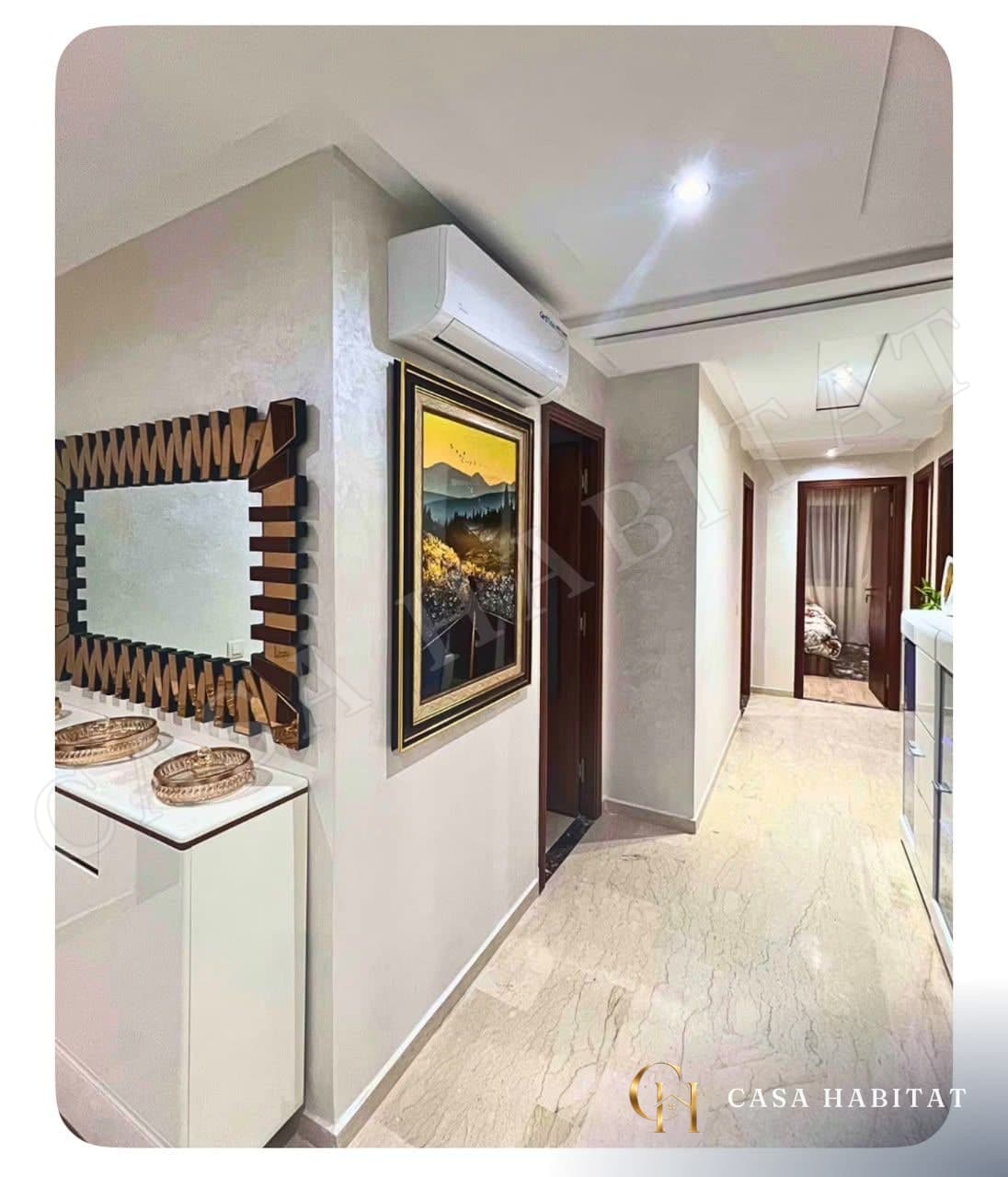 Couloir en marbre avec console blanche, miroir en bois et tableau