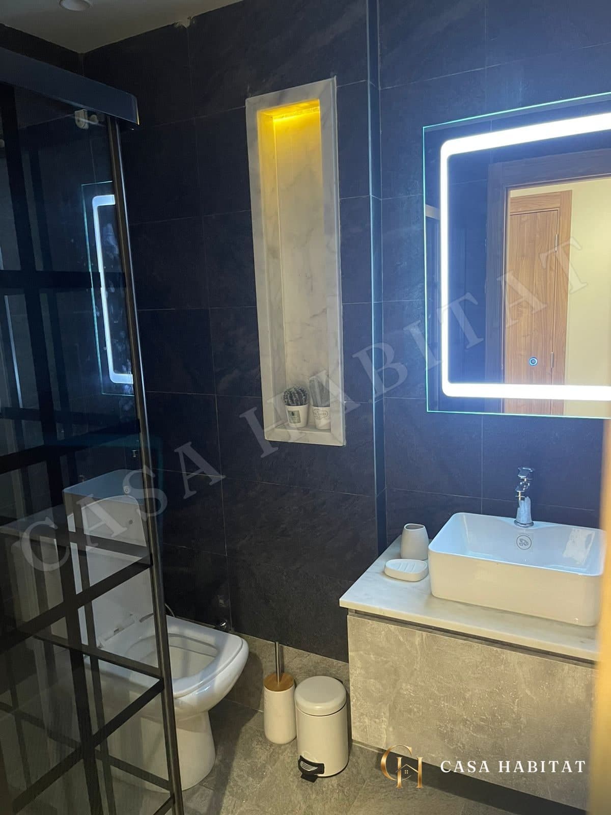 Salle de bain avec douche en verre et lavabo lumineux
