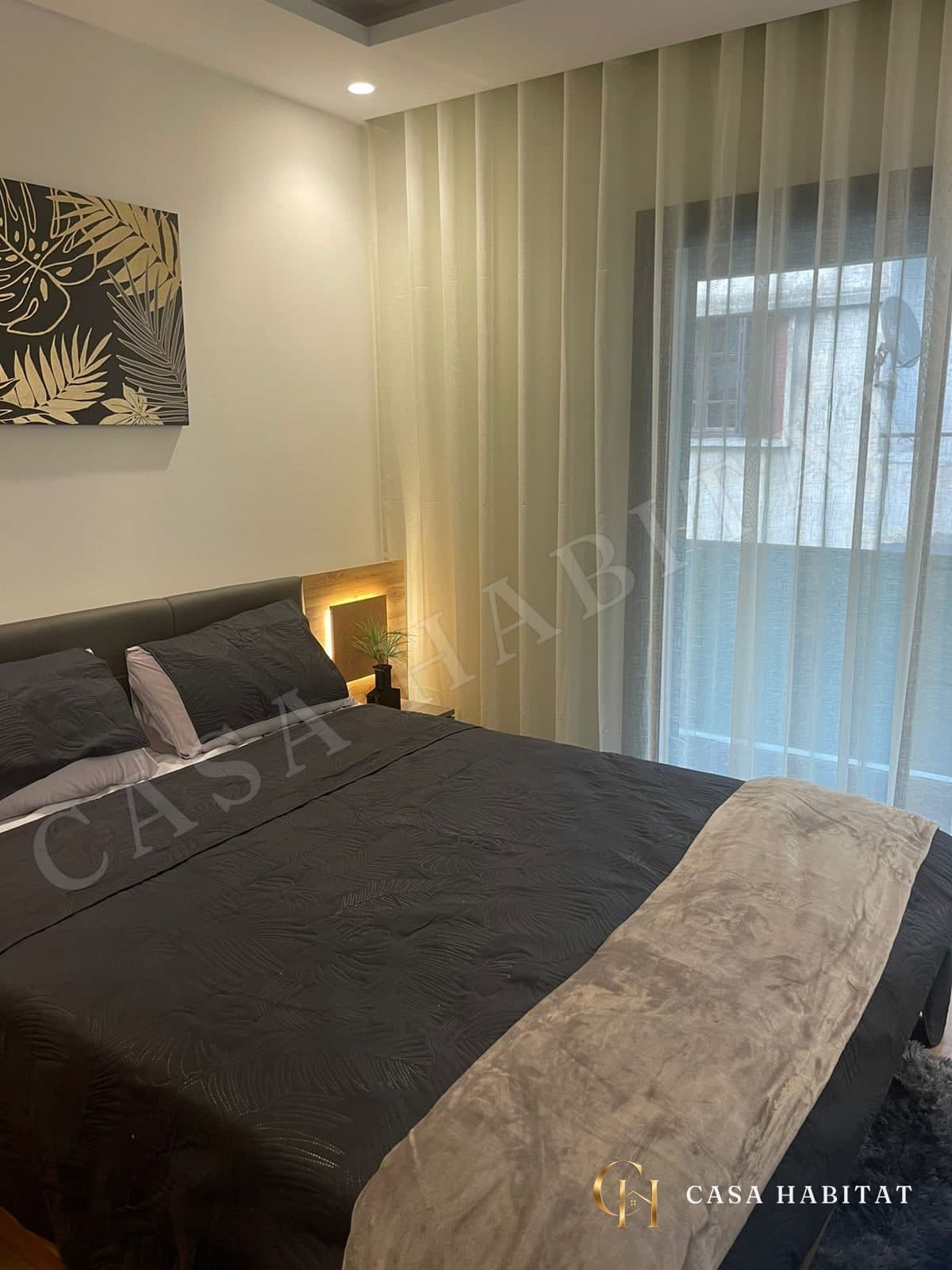 Chambre avec grand lit, couvre-lit sombre et rideaux