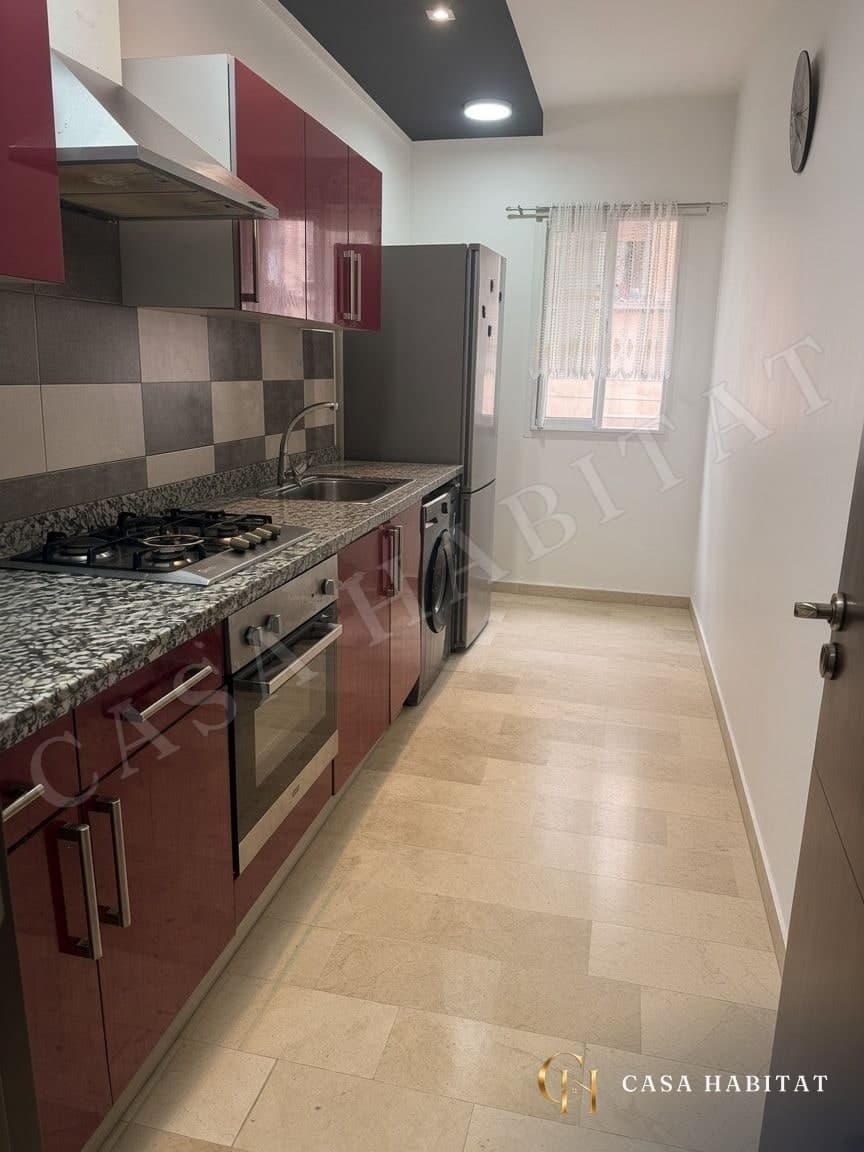 Cuisine avec plan de travail granit, plaques de cuisson et réfrigérateur