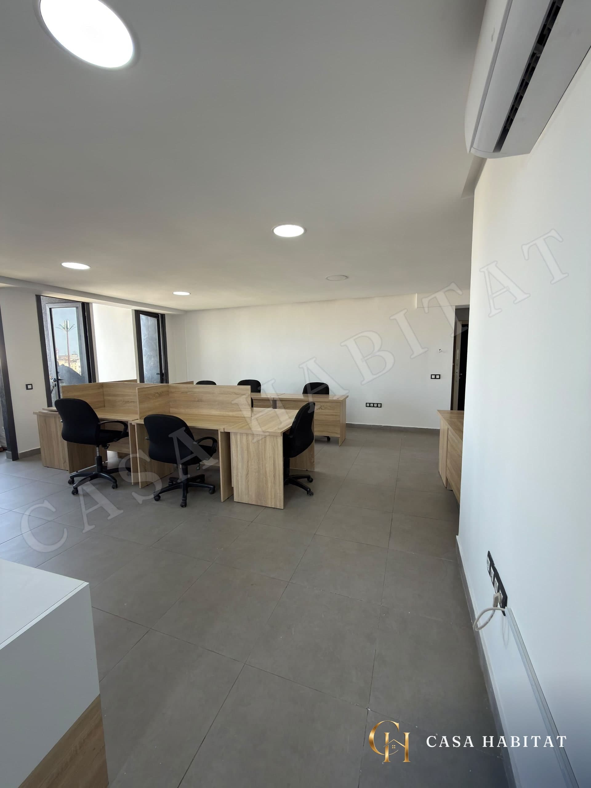 Open space avec postes de travail en bois et climatiseur mural
