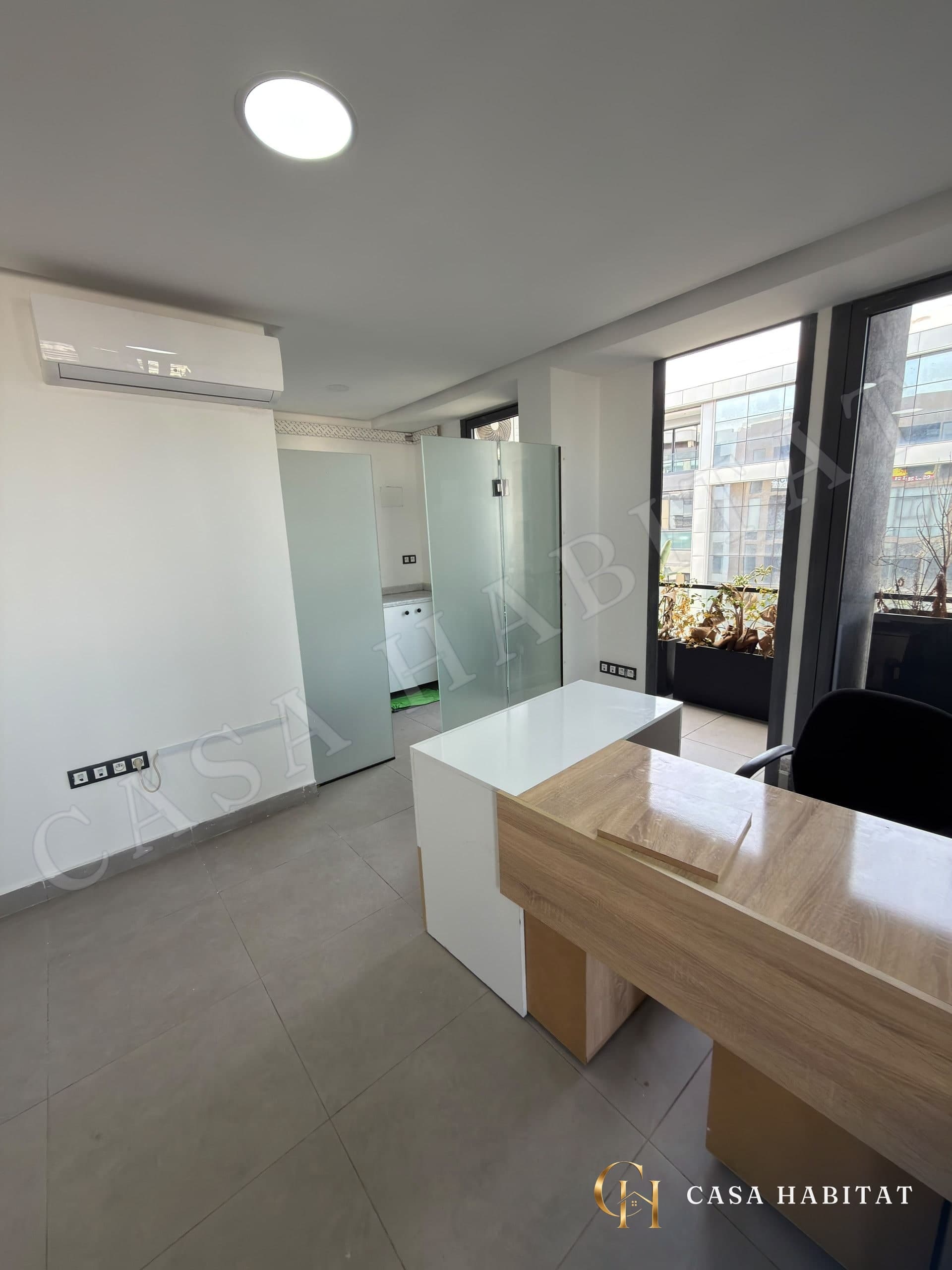 Bureau avec meuble en bois et blanc près d'une baie vitrée
