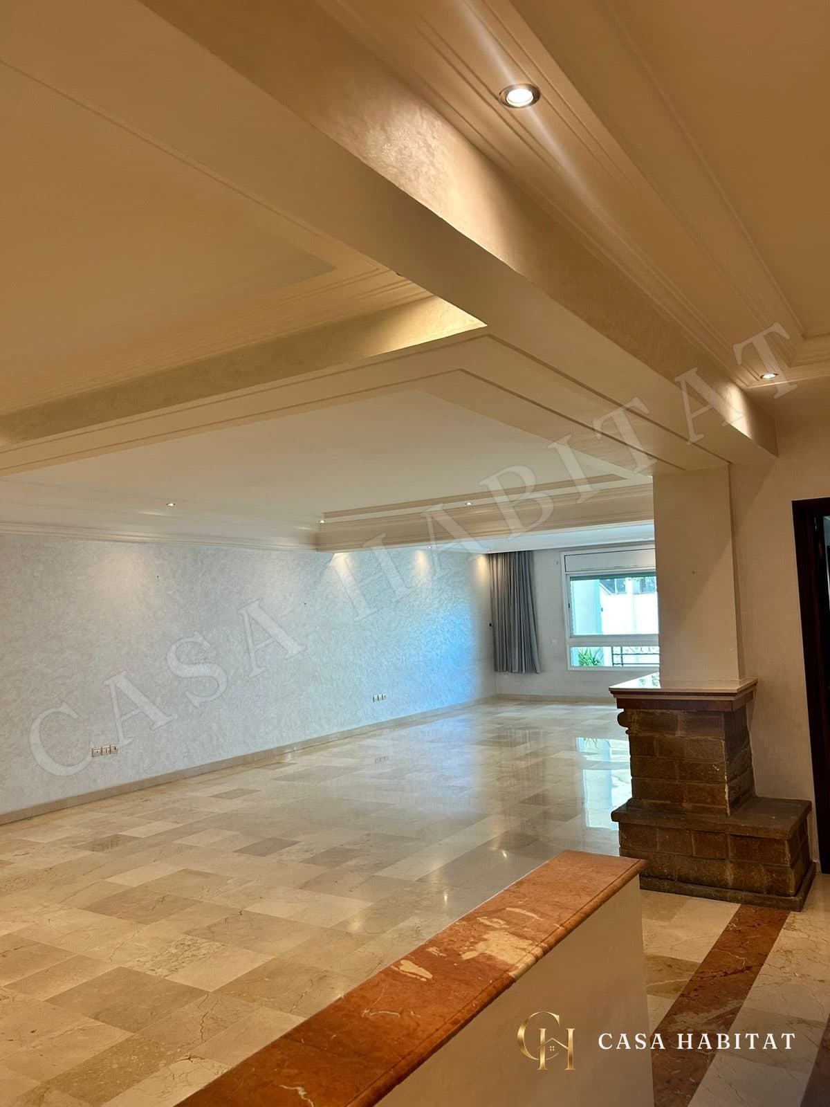 Grand salon vide avec sol en marbre et plafond à spots