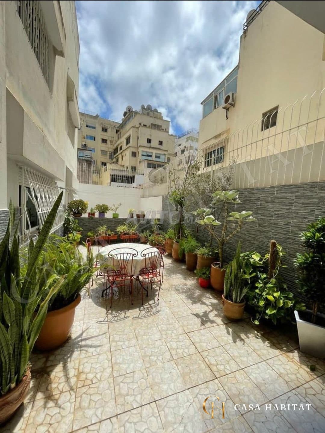 Terrasse carrelée avec table, chaises et plantes en pots