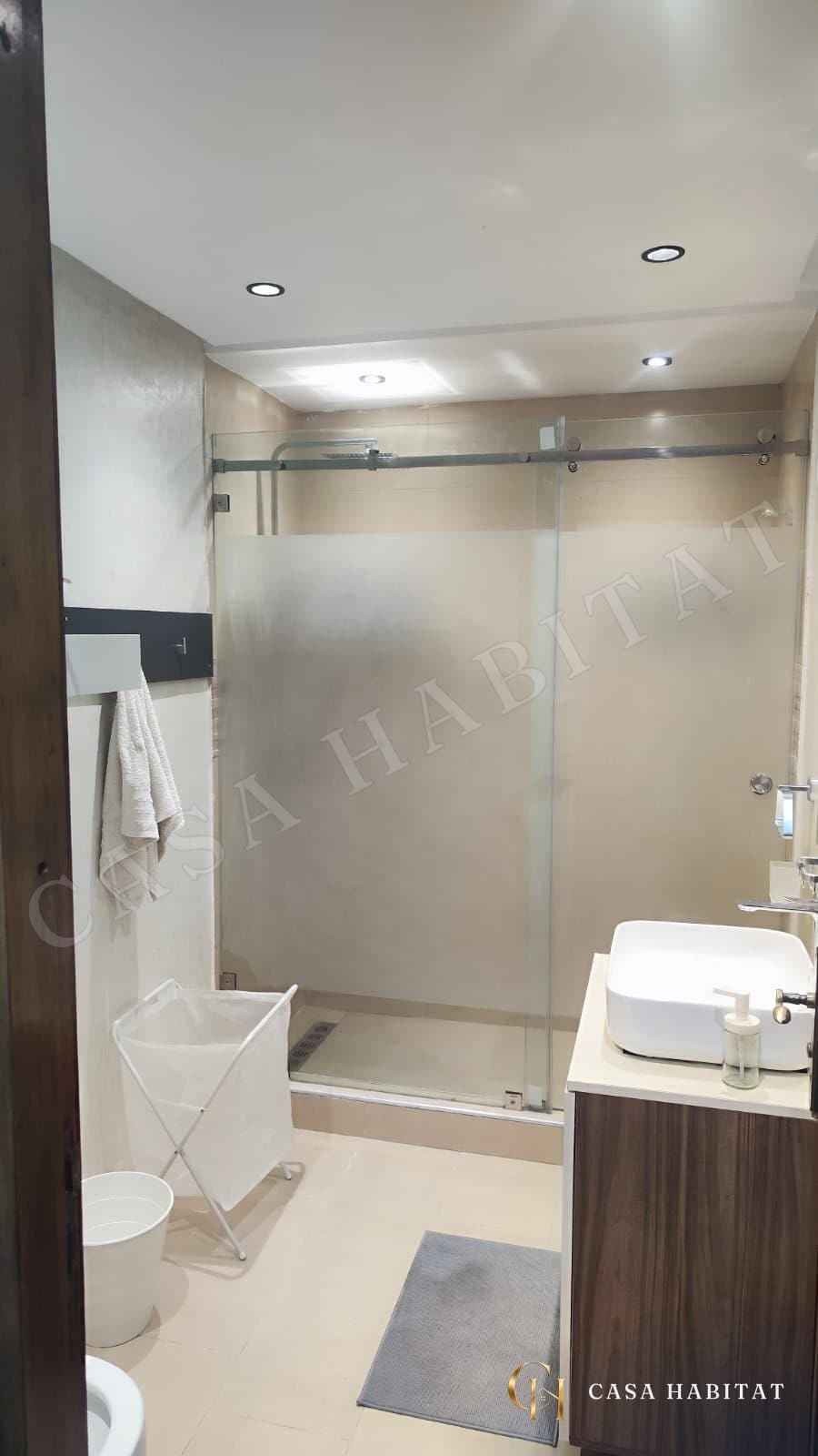 Salle de bain avec douche en verre, lavabo blanc et meuble en bois