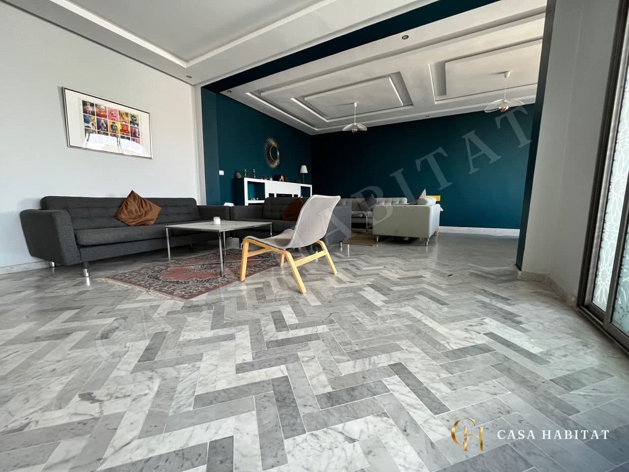 Salon avec canapés gris, tapis et table basse en verre