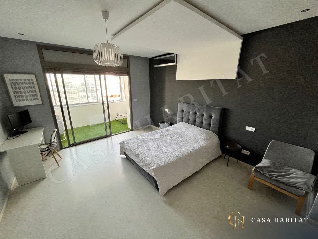 Chambre avec lit double, bureau blanc et baie vitrée sur terrasse