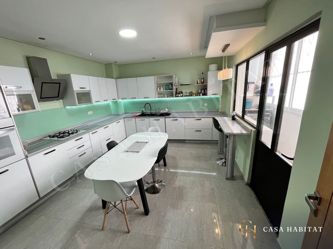 Cuisine blanche et verte avec îlot, table et chaises