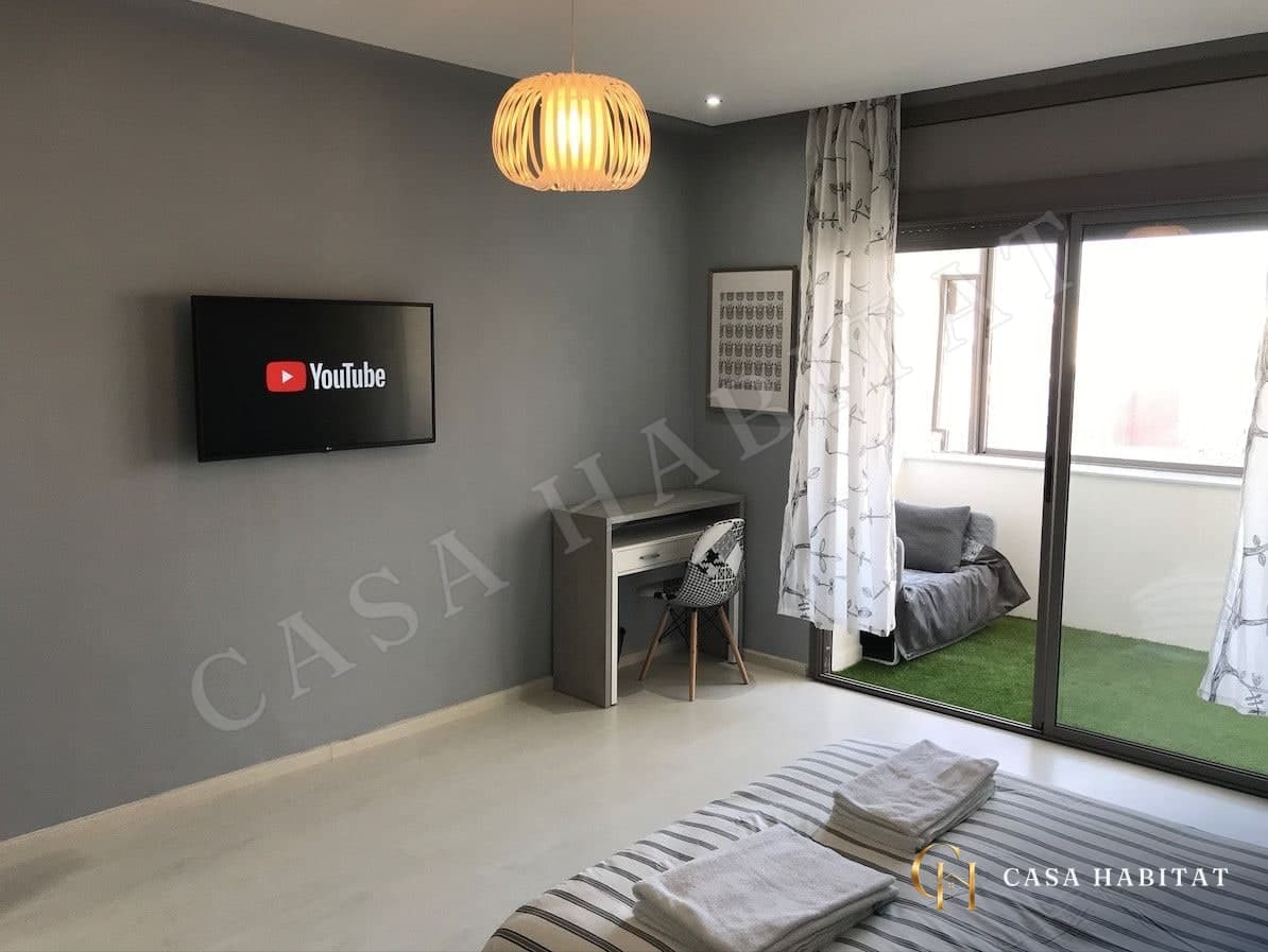 Chambre grise avec téléviseur, bureau et accès à la terrasse
