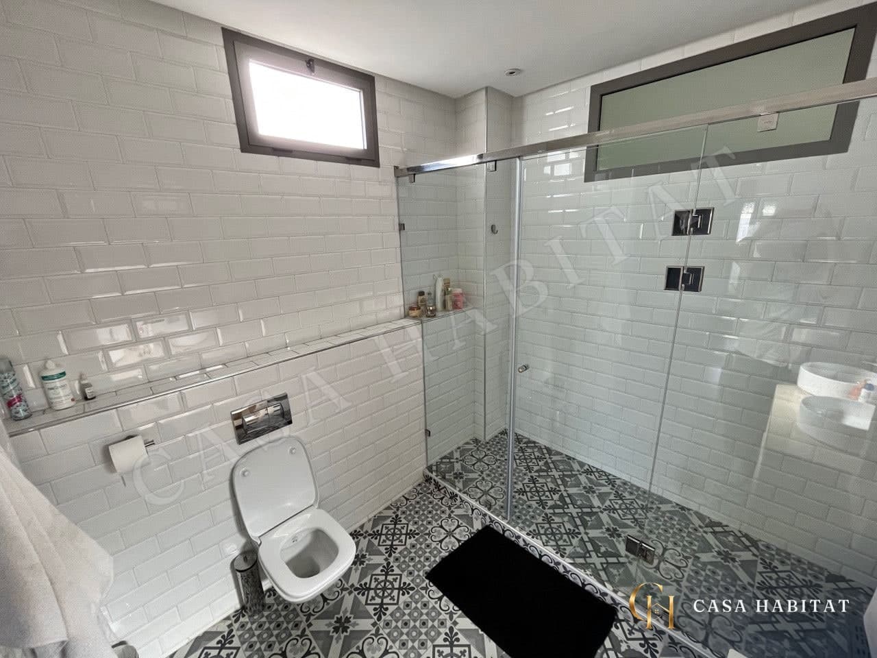 Salle d'eau avec douche vitrée, carrelage blanc et WC