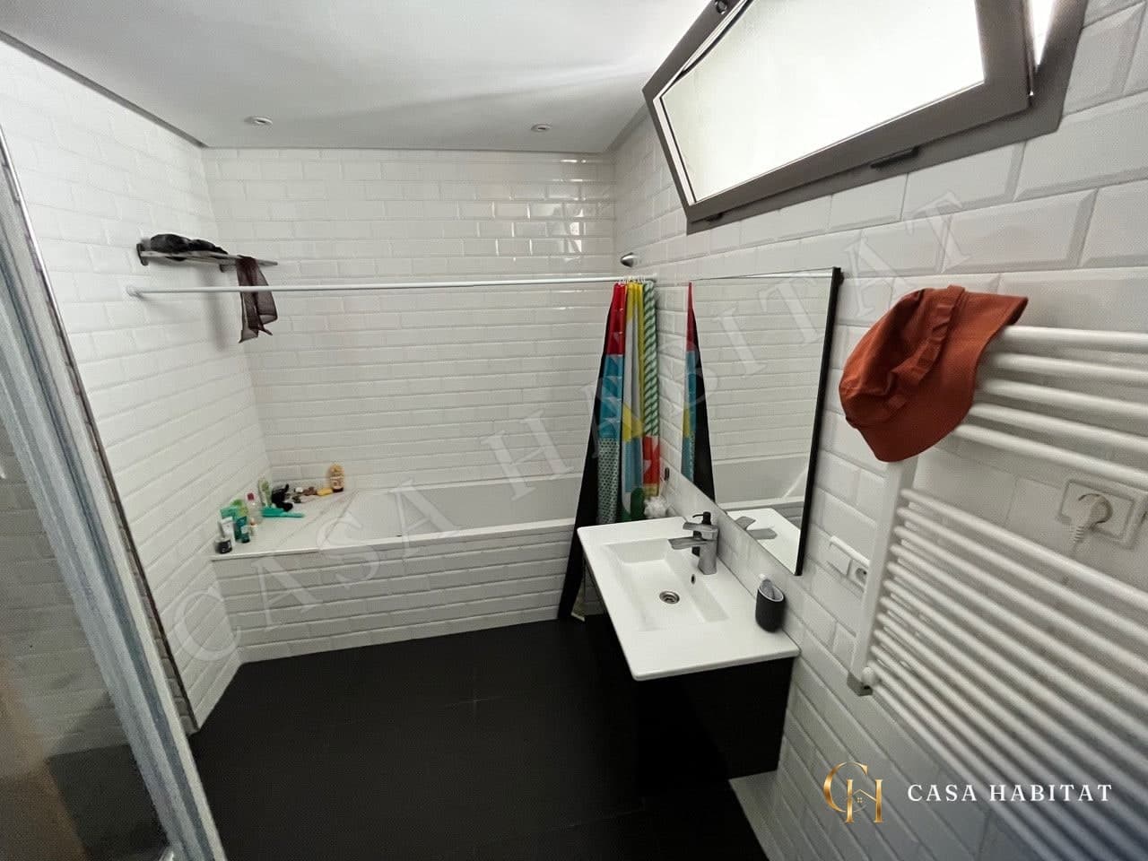 Salle de bain avec baignoire, lavabo blanc et radiateur sèche-serviettes