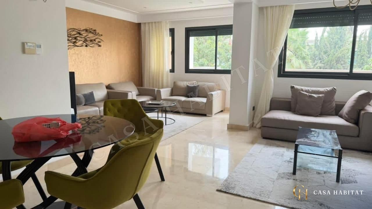 Salon avec canapés beige, table basse en verre et fenêtres sur la végétation