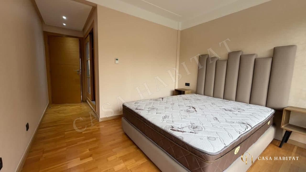 Chambre avec grand lit à tête capitonnée et parquet clair