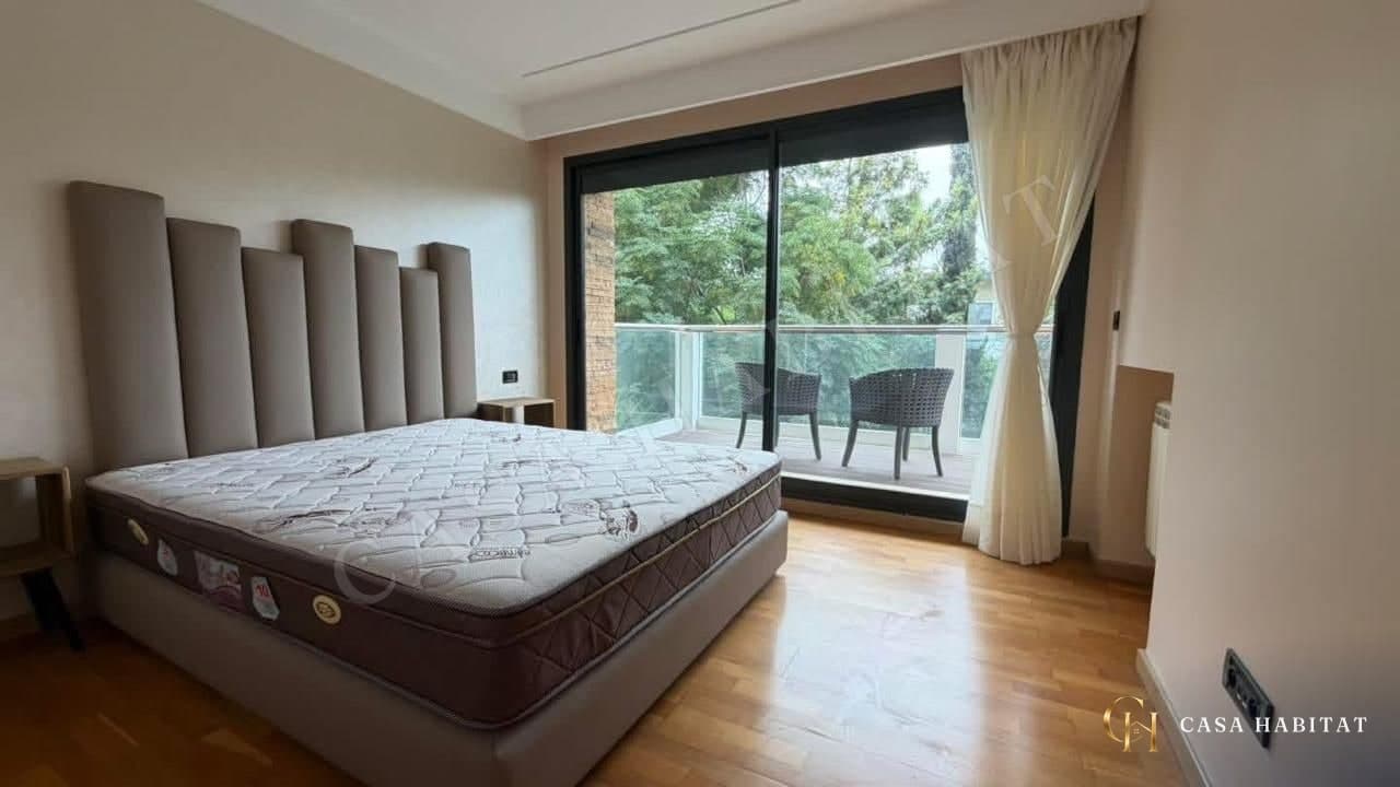 Chambre avec lit à tête capitonnée et porte-fenêtre donnant sur un balcon