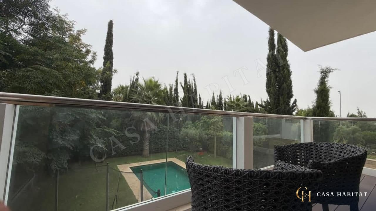 Balcon avec chaises en osier noir et vue sur la piscine et les arbres