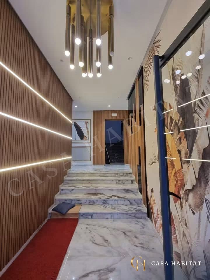 Couloir avec escalier en marbre, lustre doré et panneaux en bois