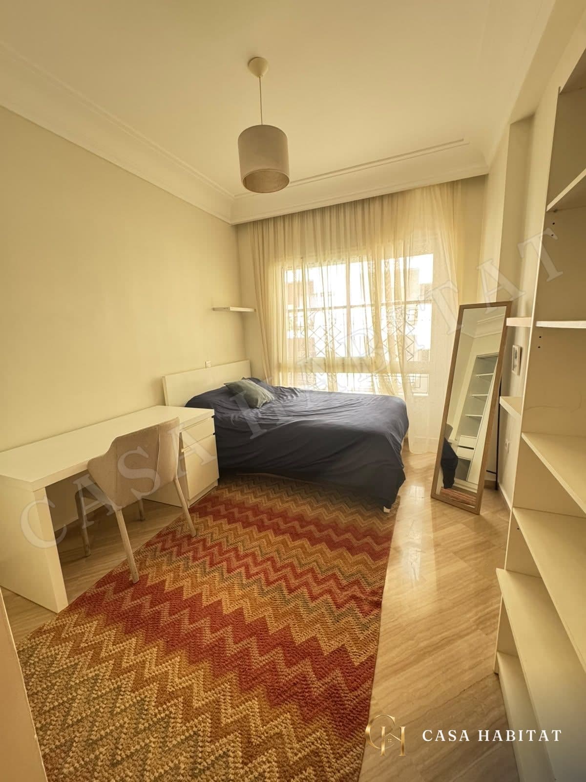 Chambre avec bureau blanc, lit et grand miroir