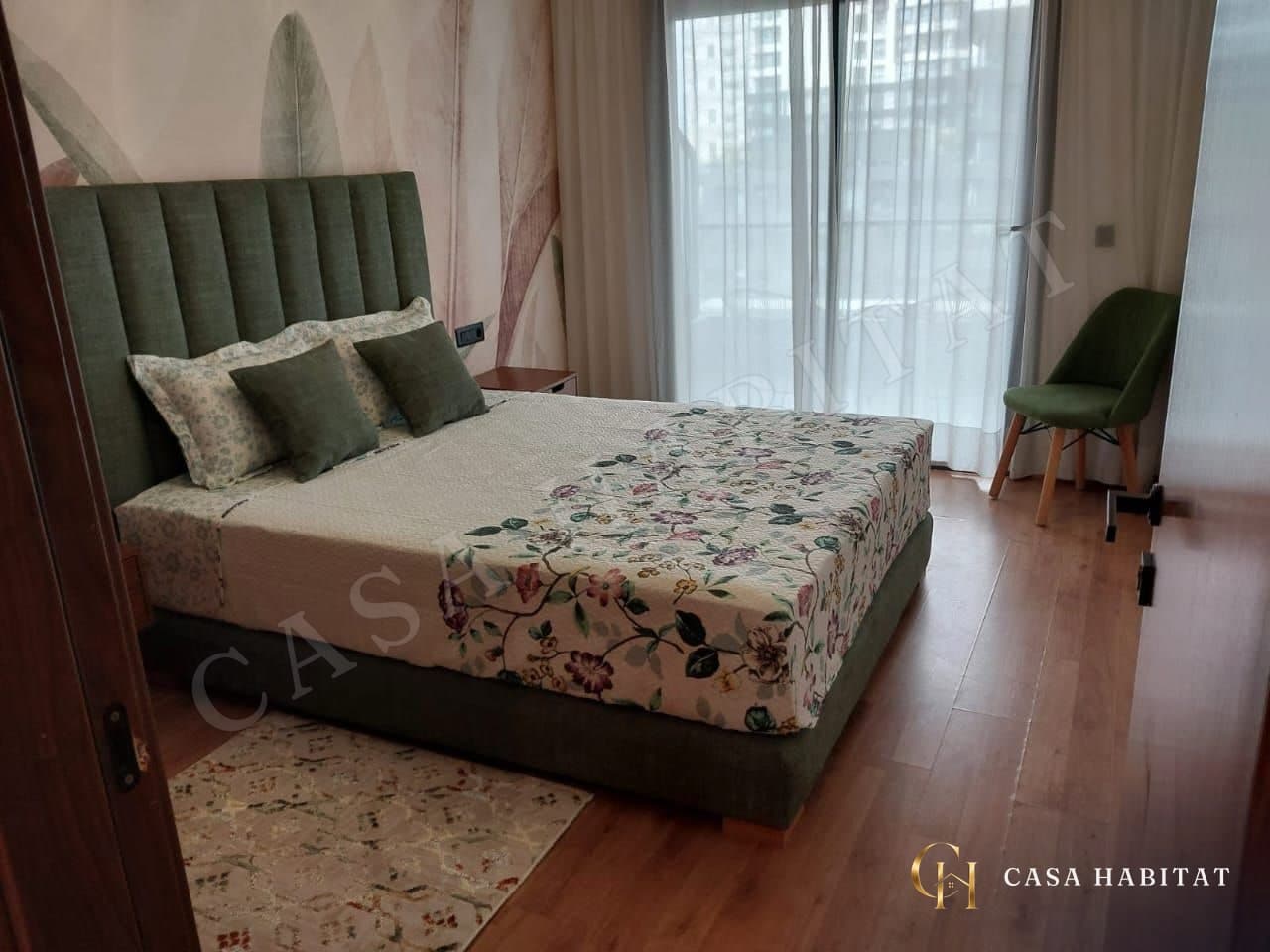 Chambre avec lit à tête capitonnée et fauteuil vert