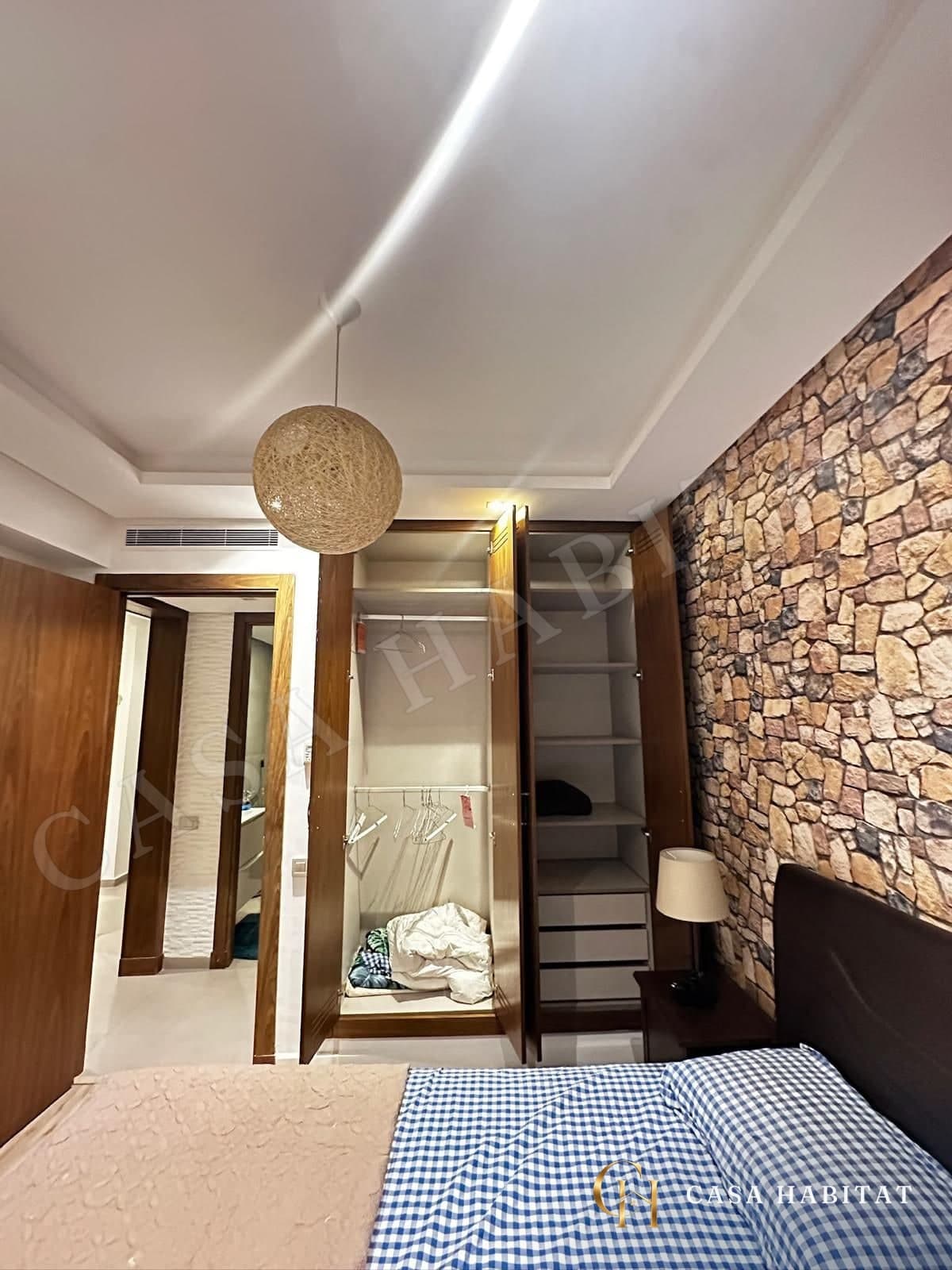Chambre avec penderie ouverte et mur en pierre
