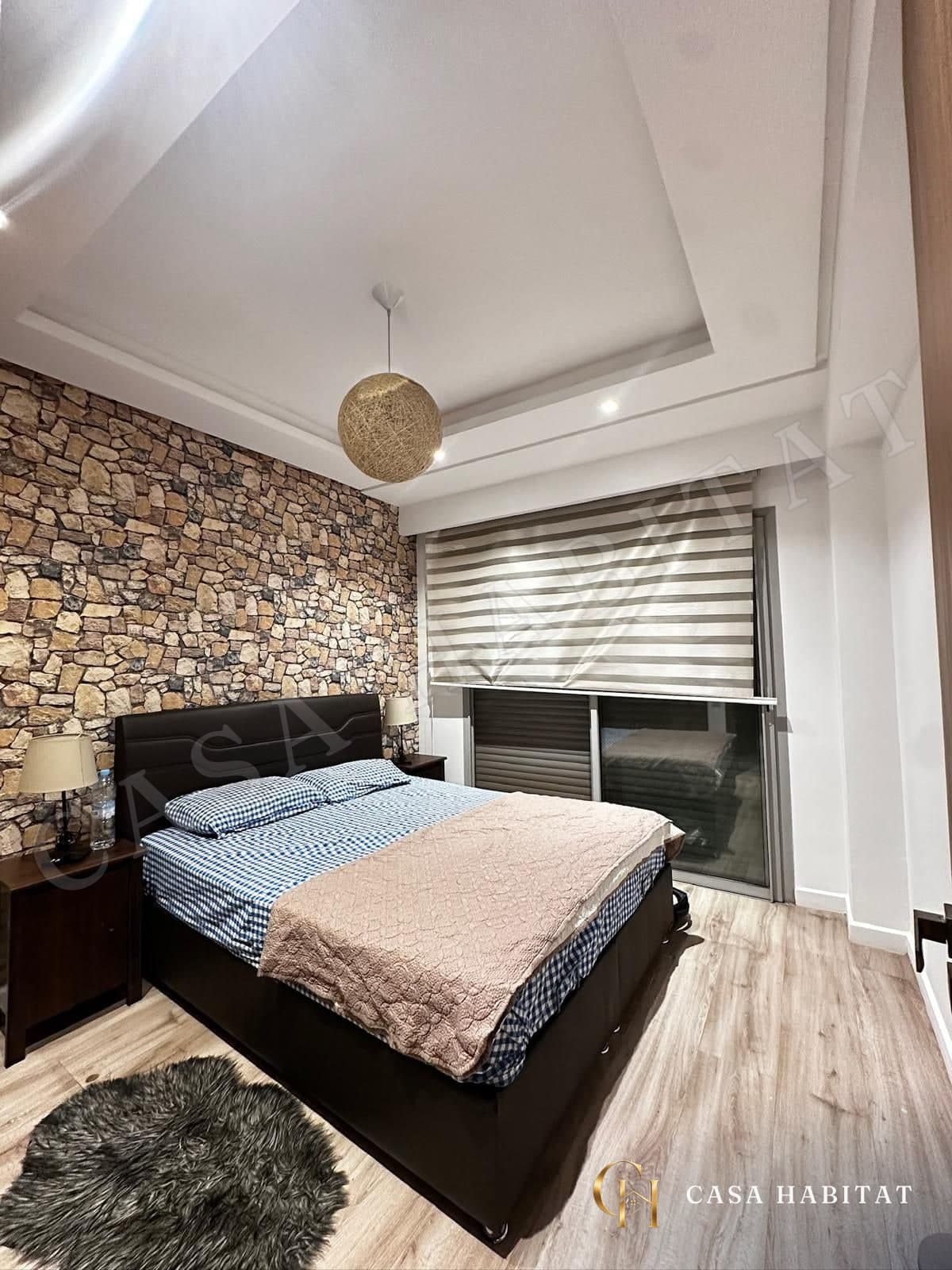 Chambre avec lit double, mur en pierre et store