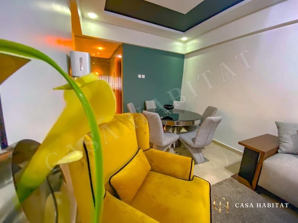 Coin repas avec fauteuil jaune et plante près d'un canapé gris
