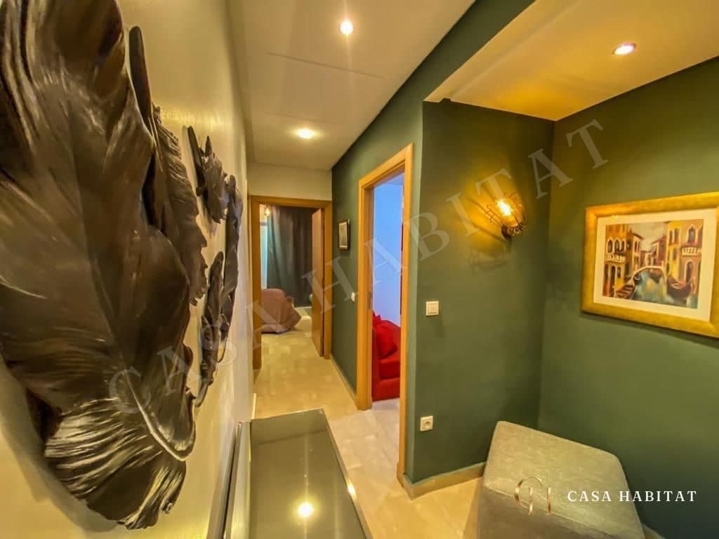Couloir vert avec tableau doré, sculpture murale et chambre au fond