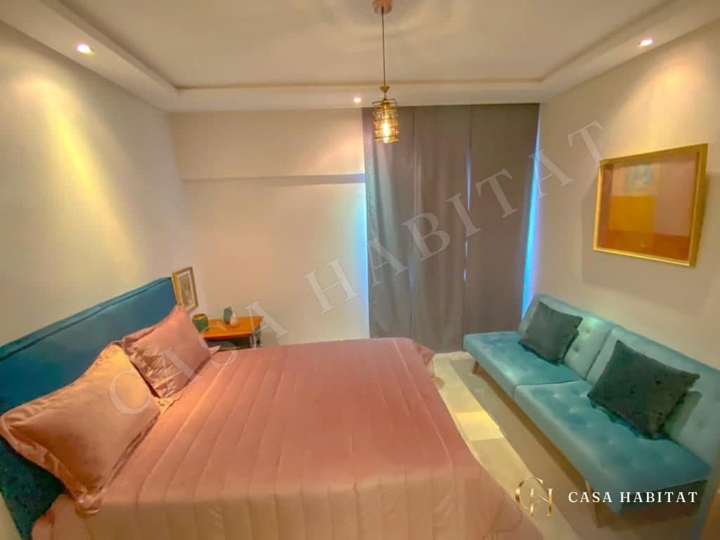 Chambre avec lit rose, canapé bleu et tableau doré
