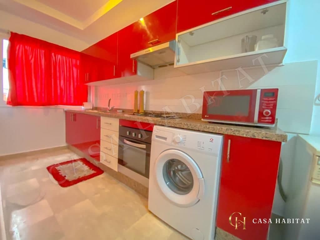 Cuisine rouge avec lave-linge, four, micro-ondes et rideau rouge