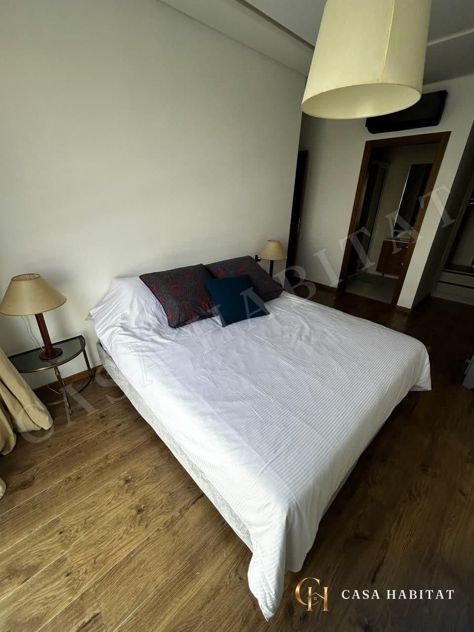 Chambre avec lit blanc, tables de chevet et accès à la salle d'eau