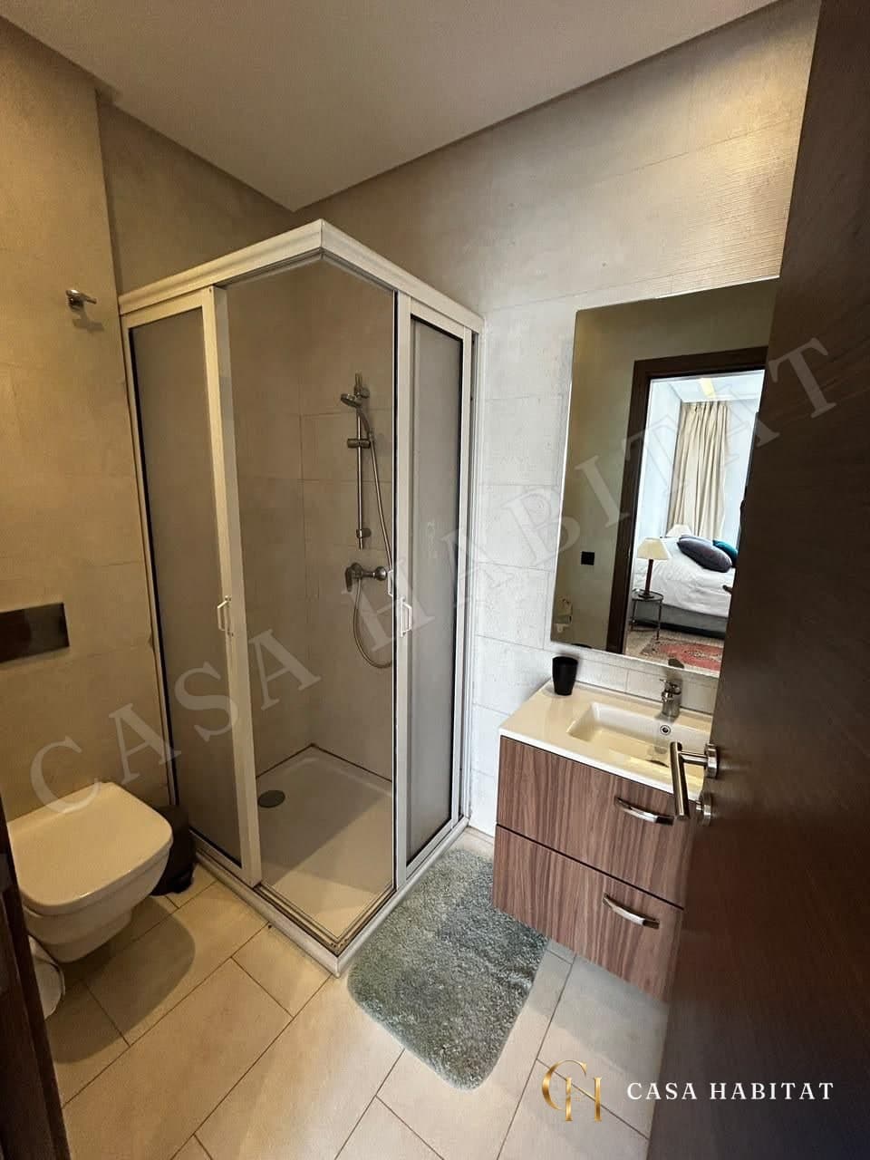 Salle d'eau avec douche en cabine, lavabo et meuble en bois