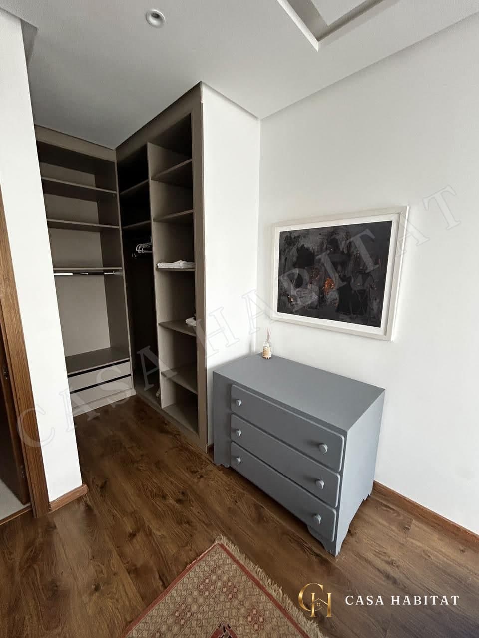 Dressing avec étagères et commode grise sous un tableau