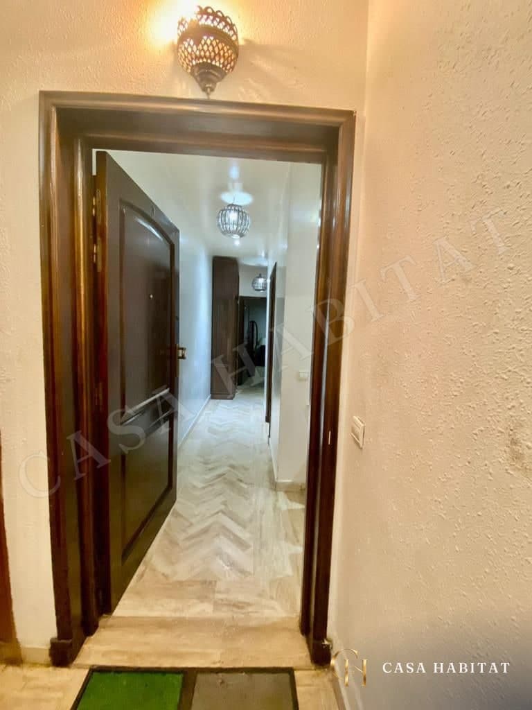 Entrée avec porte en bois, applique murale et vue sur le couloir