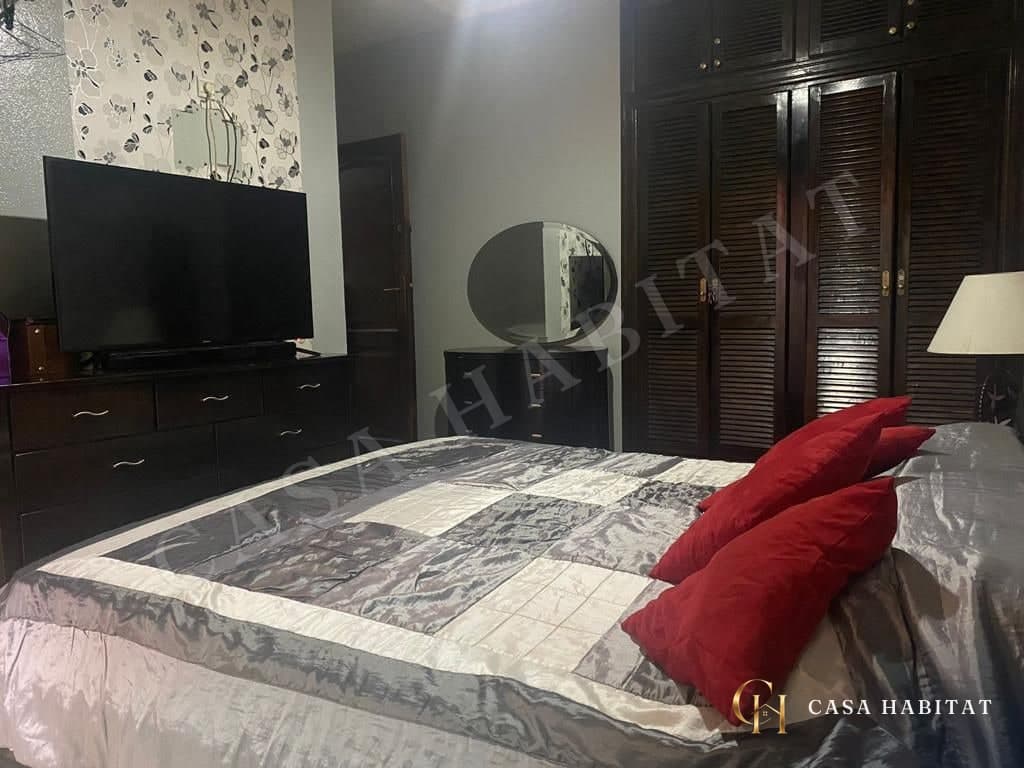 Chambre avec lit, téléviseur mural et armoires en bois foncé