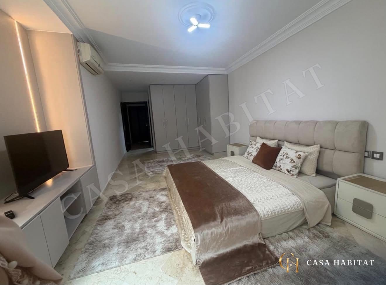 Chambre avec lit capitonné, tapis et placards blancs