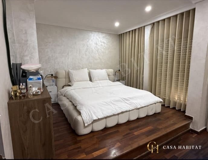 Chambre avec grand lit blanc et rideaux beiges