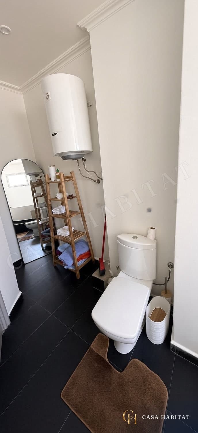 Toilettes avec chauffe-eau mural et étagère à serviettes