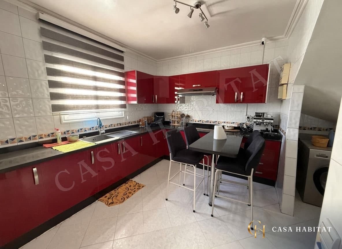 Cuisine rouge avec évier, plaque et table haute