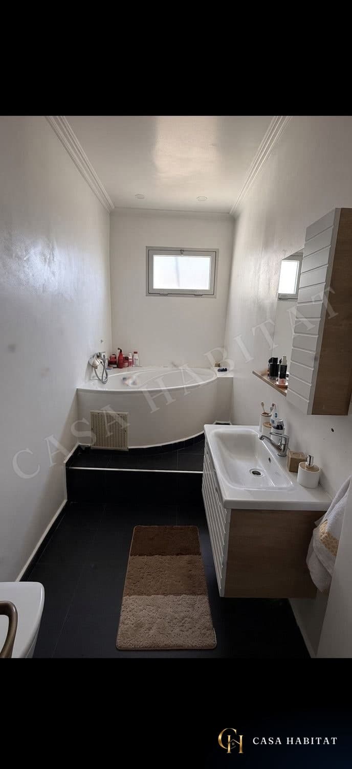 Salle de bain avec baignoire d'angle et meuble vasque
