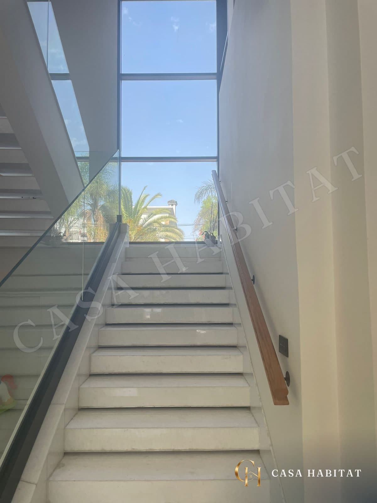 Escalier blanc en marbre avec rambarde en verre et fenêtre haute