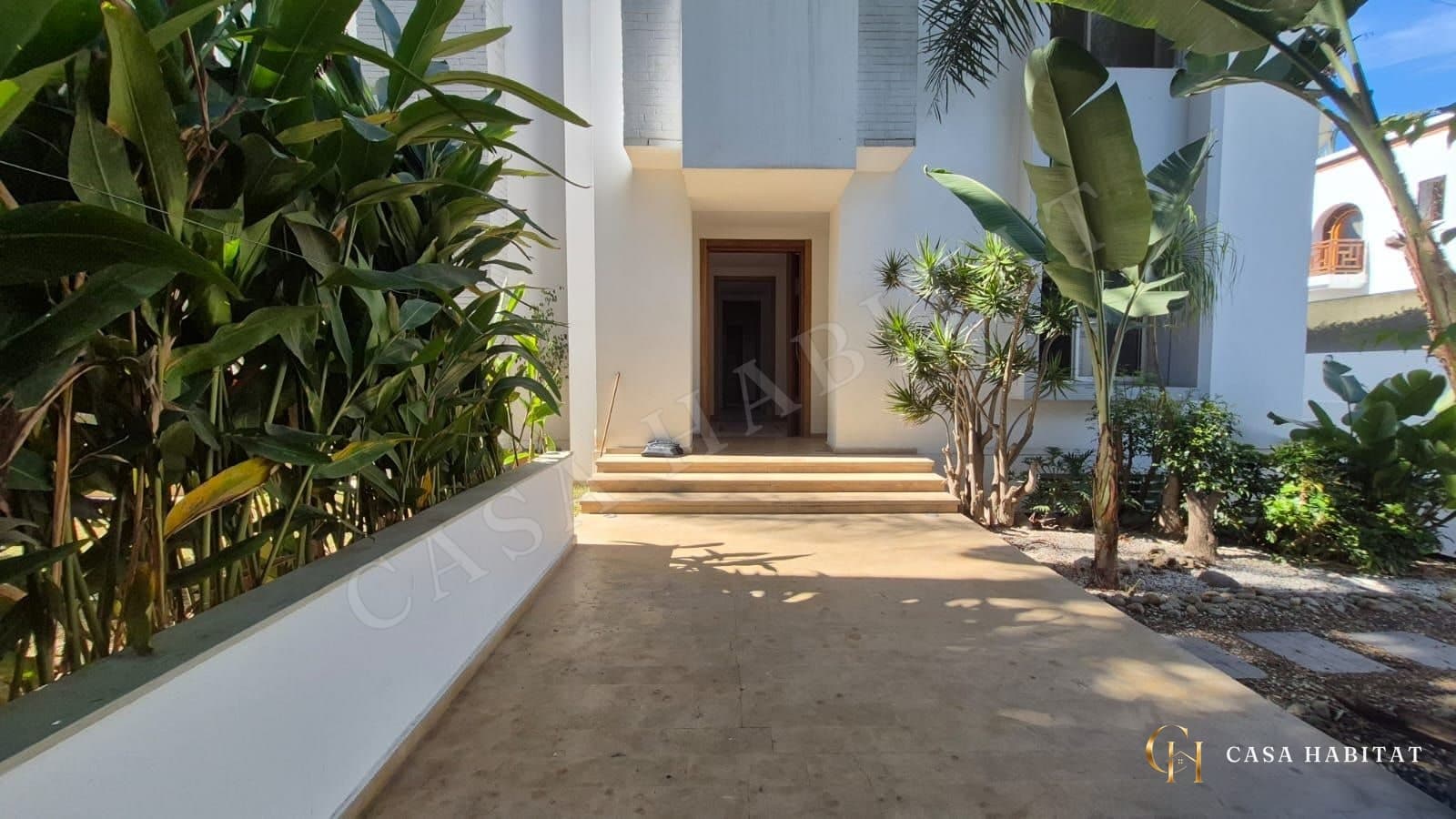 Entrée de maison avec escalier, plantes et allée en pierre