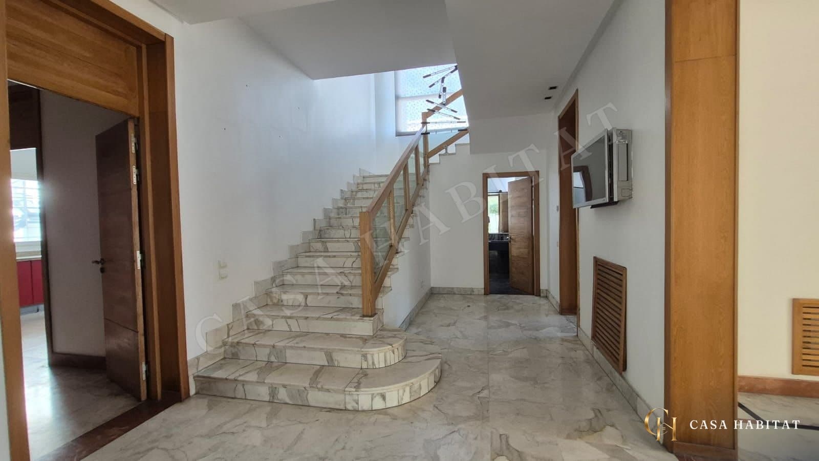 Hall avec escalier en marbre, garde-corps en verre et portes en bois
